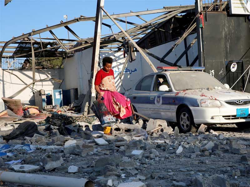 مهاجر يلتقط ملابس من بين الأنقاض في مركز احتجاز للمهاجرين الأفارقة الذين أصيبوا في غارة جوية في ضاحية تاجوراء بالعاصمة الليبية طرابلس