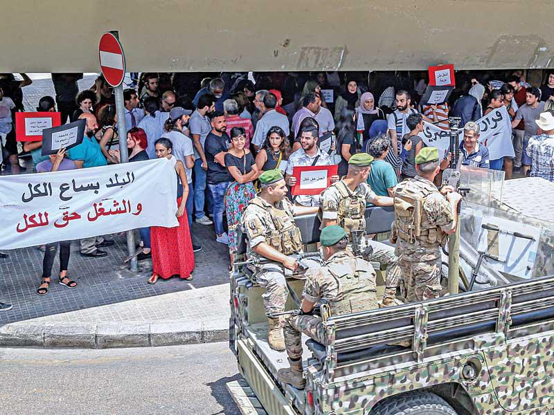 دورية للجيش اللبناني تمرّ قرب تظاهرة لنشطاء لبنانيين وسوريين وفلسطينيين أمس احتجاجاً على قانون العمل الجديد         (اي بي ايه)