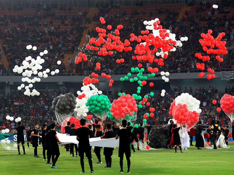 الممثلون يطلقون بالونات خلال حفل أقيم قبل مباراة لكرة القدم بين العراق ولبنان في بطولة غرب آسيا في ملعب مدينة كربلاء الرياضية