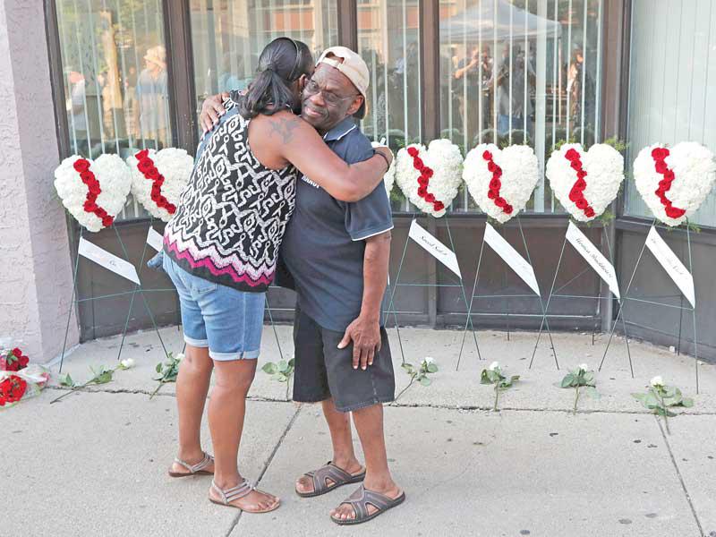 أميركيان يواسي كل منهما الآخر أمام موقع خصص لتكريم الضحايا الـ 9 في أوهايو (اي بي أيه)