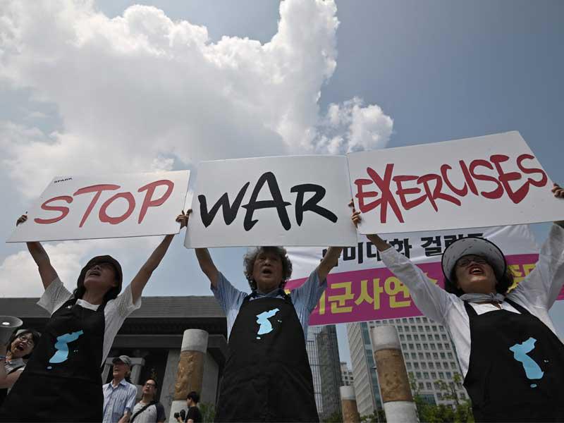 ناشطون مناهضون للحرب يحملون لافتات كتب عليها أوقفوا تمارين الحرب