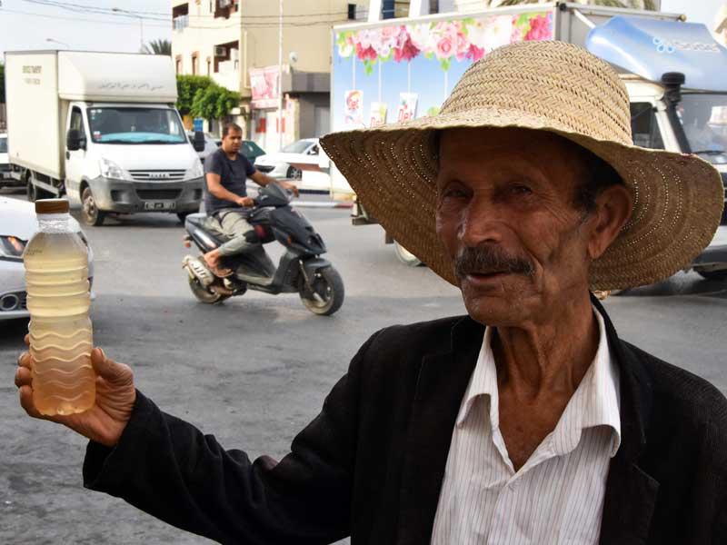 بائع متجول يحمل زجاجة من مشروب اللاقمي ، في مدينة قابس بجنوب غرب تونس