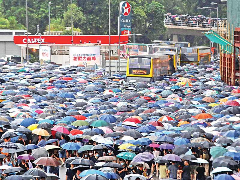 مواطنون في هونغ كونغ يتظاهرون أمس تحت المطرt (رويترز) 