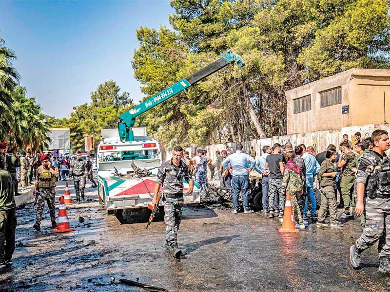 عناصر أمن ومدنيون في موقع انفجار السيارة المفخّخة في القامشلي أمس (أ ف ب)