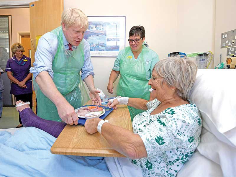 جونسون يقدّم الأكل إلى مريضة خلال زيارته أمس الأول لمستشفى في جنوب إنكلترا (أ ف ب)