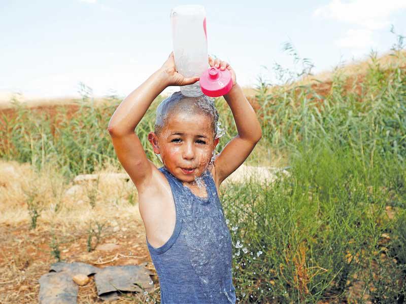 طفل فلسطيني يرش نفسه بالماء بسبب الحر في الضفة الغربية أمس (رويترز)