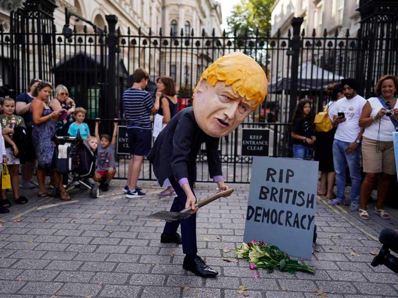 بريطاني بقناع جونسون خلال احتجاج بلندن أمس (رويترز)