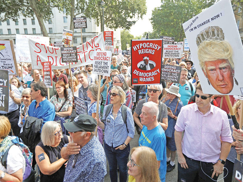 معارضون يتظاهرون في لندن أمس رافعين صوراً لترامب (رويترز)