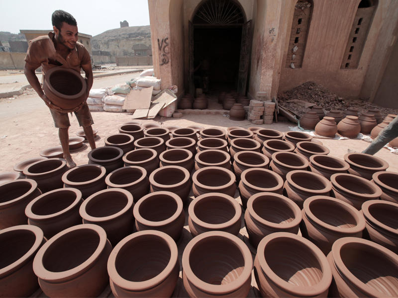 صانع أوانٍ فخارية بانتظار تجفيفها قبل عرضها للبيع في القاهرة (إي بي آيه)
