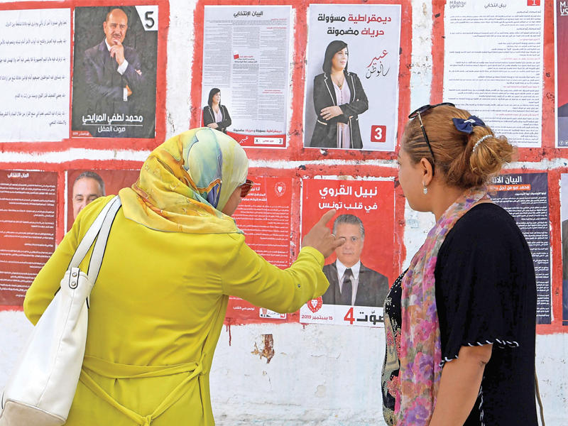 تونسيتان أمام ملصقات المرشحين بالعاصمة أمسt (أ ف ب)