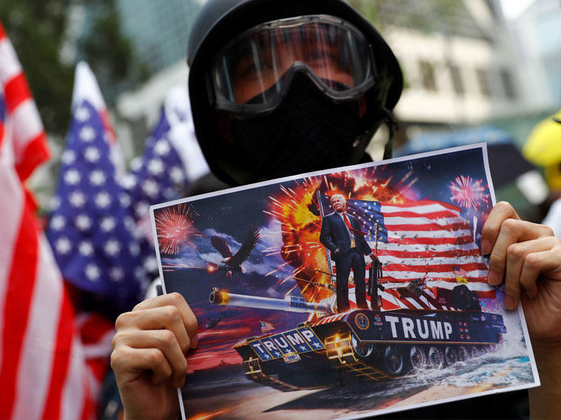 متظاهر من هونغ كونغ يحمل صورة ترامب خلال مسيرة إلى القنصلية الاميركية أمس (رويترز)