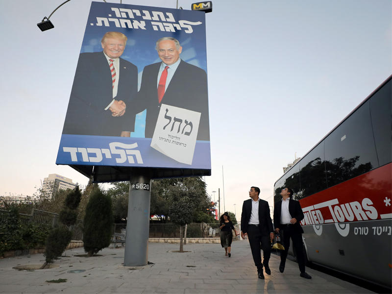 إسرائيليون بجوار لافتة انتخابية لـ«حزب ليكود» في القدس المحتلة أمس الأول   (رويترز)