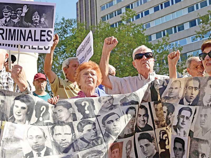 إسبان يحملون صور ضحايا فرانكو خارج المحكمة العليا بمدريد أمس (أ ف ب)