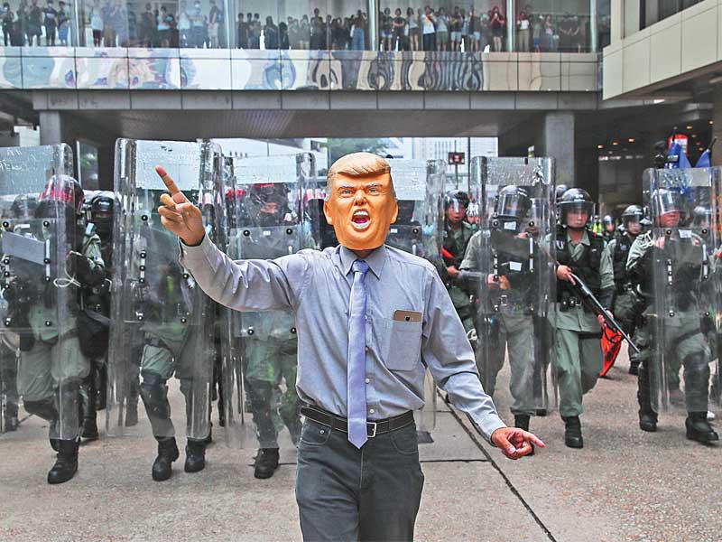 متظاهر يضع قناعا يجسد وجه الرئيس الأمريكي دزنالد ترامب خلال تظاهرة مطالب بالديمقراطية في هونغ كونغ أمس (اي بي ايه)