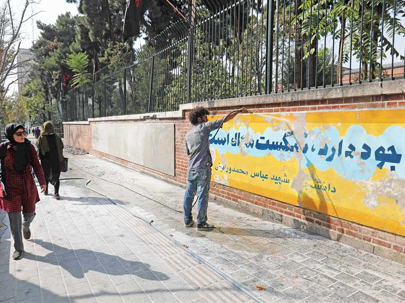 إيراني يزيل جدارية قديمة لاستبدال أخرى بها على جدار السفارة الأميركية بطهران أمس، بالتزامن مع حلول الذكرى الـ40 لاقتحامها عام 1979 (أ ف ب)