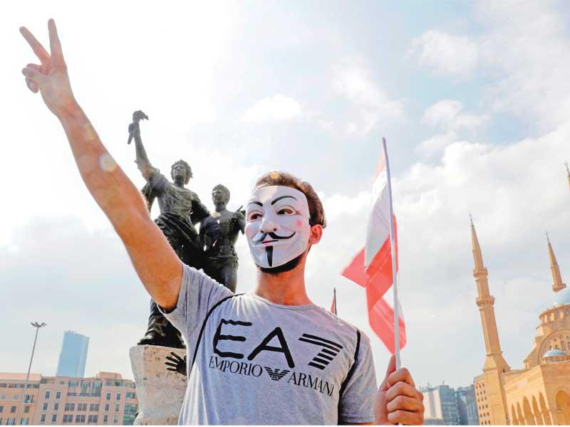 لبناني يضع قناعاً لغاي فوكس ويرسم شارة النصر في ساحة الشهداء وسط بيروت أمس (أ ف ب)
