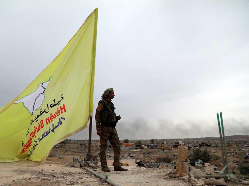 مقاتل من القوات الديمقراطية السورية (SDF) جانب العلم الأصفر للقوات الديمقراطية السورية المدعومة من الولايات المتحدة