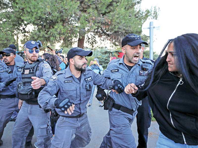 عناصر من الشرطة الإسرائيلية يعتدون على فلسطينية في القدس أمس خلال تظاهرة خارج محكمة تشهد جلسة استماع لفلسطيني متهم بقتل شاب إسرائيلي (رويترز) 