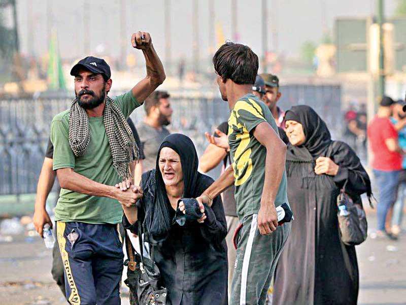 محتجون عراقيون يساعدون مسنّة خلال تظاهرات في بغدادn