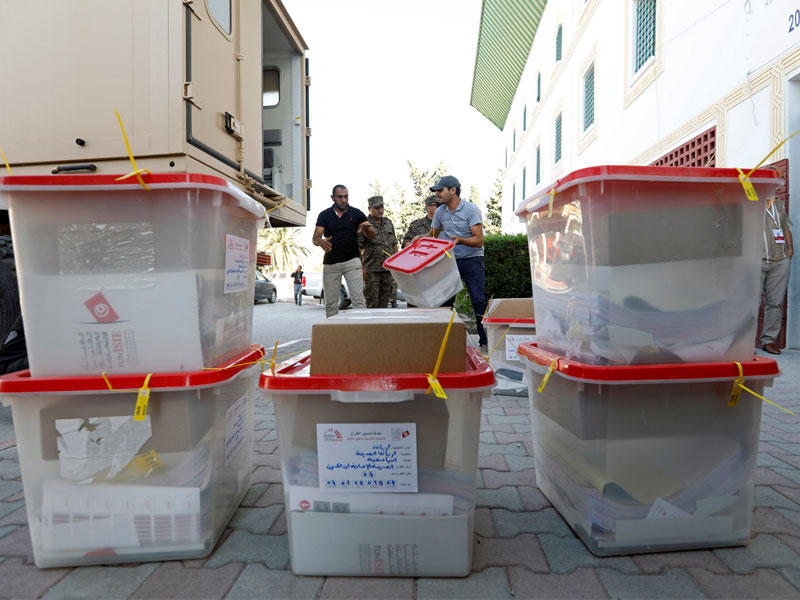 الجنود يقفون حذرًا أثناء قيام وكلاء الاقتراع بنقل صناديق الاقتراع والمواد الانتخابية ليتم توزيعها على مراكز الاقتراع ، قبل الانتخابات البرلمانية التي ستجري يوم الأحد في تونس