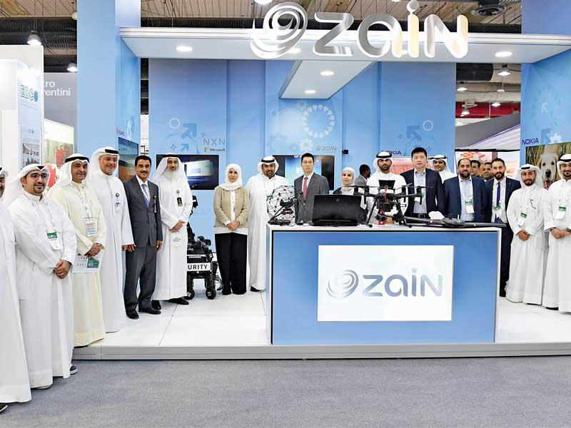 الروضان ووليد البدر يتوسطان فريق «زين» في جناح الشركة