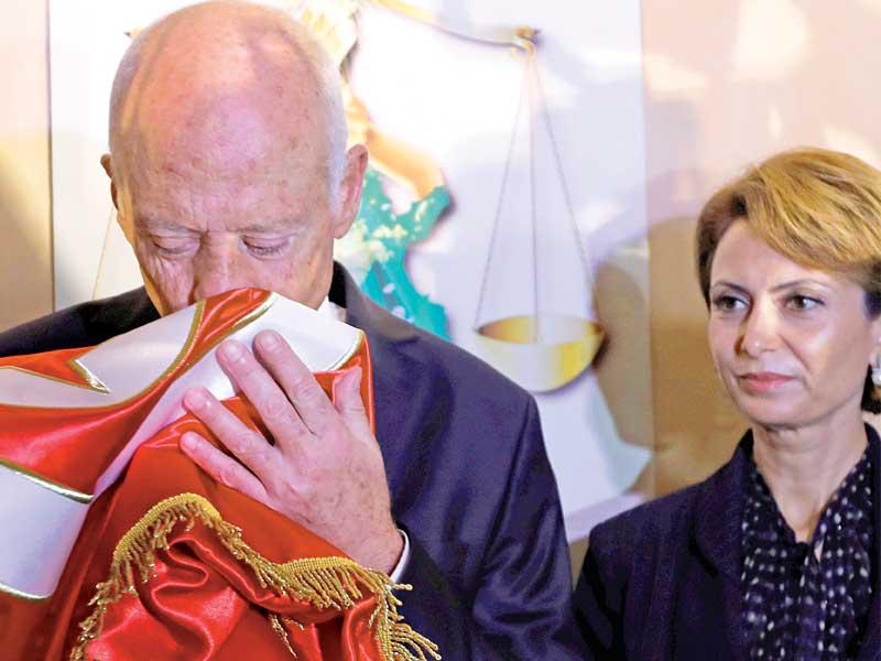 سعيد يقبّل علم تونس وإلى جانبه زوجته إشراف شبل، عقب إعلان تقدمه مساء أمس الأولt          (رويترز)