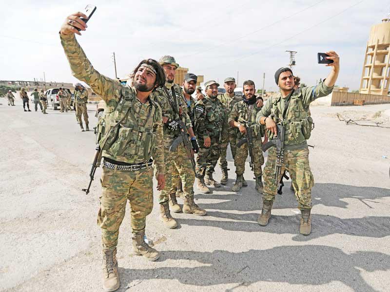 مقاتلون سوريون موالون لأنقرة يلتقطون صوراً في تل أبيض أمس الأولt(رويترز)