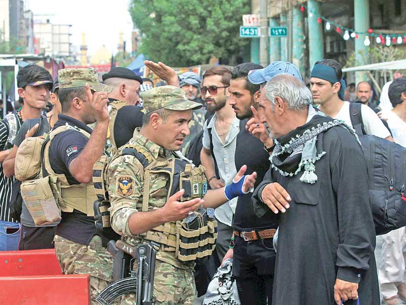 عناصر أمنية عراقية تفتّش الزوار الشيعة في مدينة كربلاء أمس (رويترز)