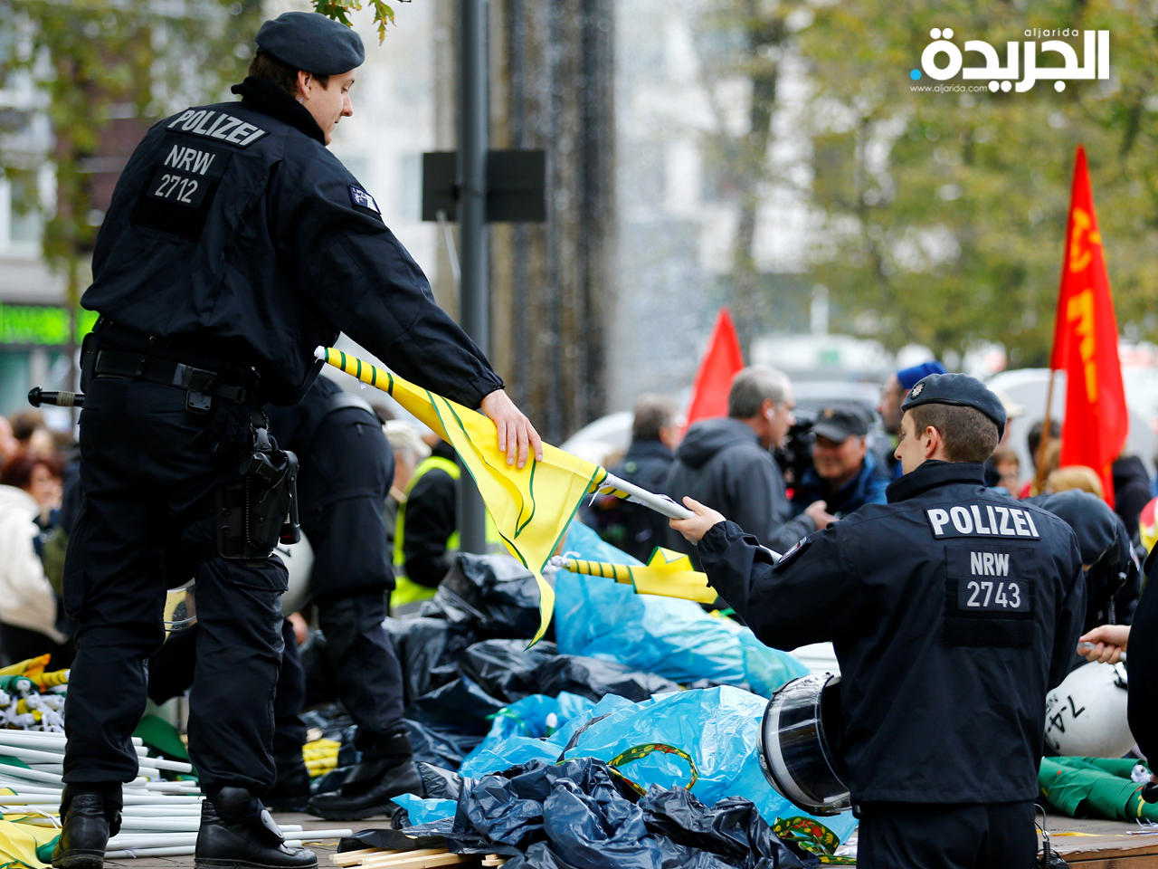 عناصر الشرطة شرطة يفحصون أعلام المتظاهرين الأكراد في كولونيا