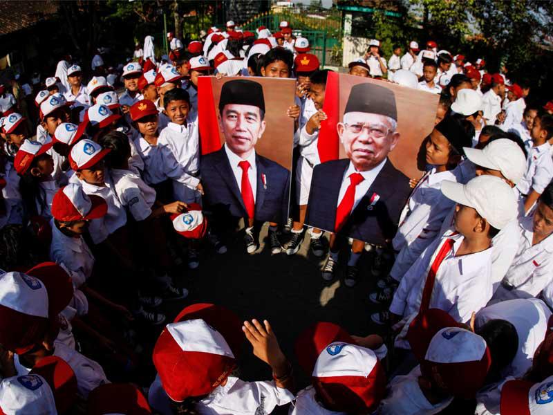 الطلاب يحملون صور الرئيس الإندونيسي جوكو ويدودو ونائب الرئيس معروف أمين خلال حفل أقيم بمناسبة تنصيبه
