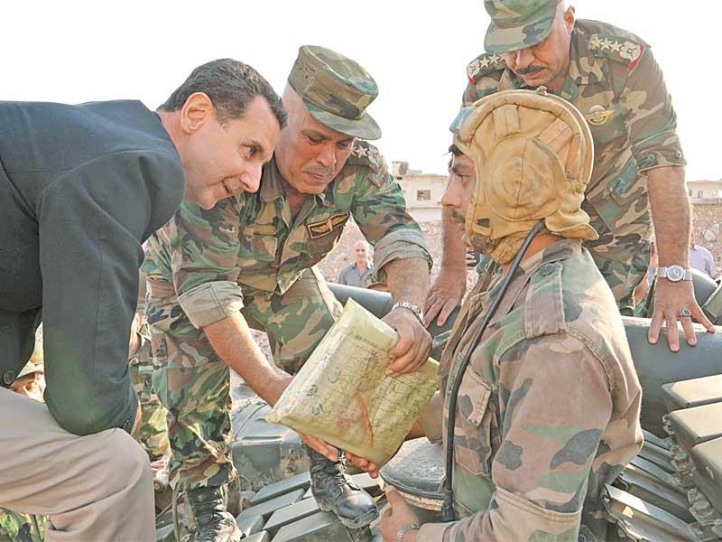 الأسد متحدثاً لجندي فوق دبابة على مشارف إدلب أمس الأول        (أ ف ب)