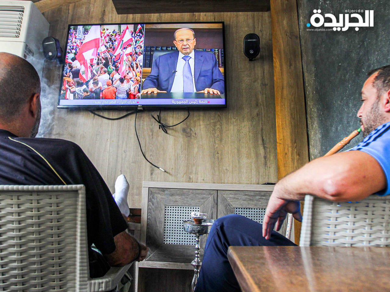 لبنانيان يتابعان كلمة الرئيس اللبناني ميشال عون عبر التلفاز