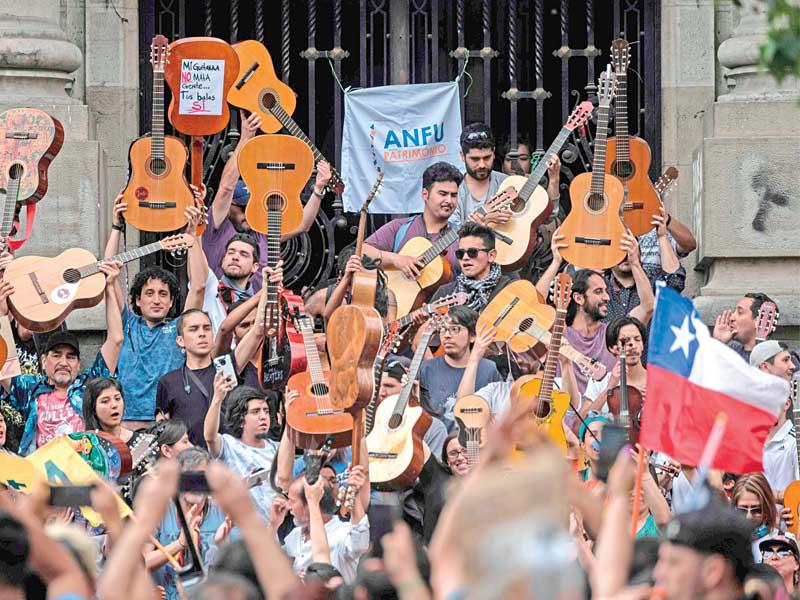 متظاهرون يغنّون خلال مسيرة في سانتياغو أمس الأول (أ ف ب)