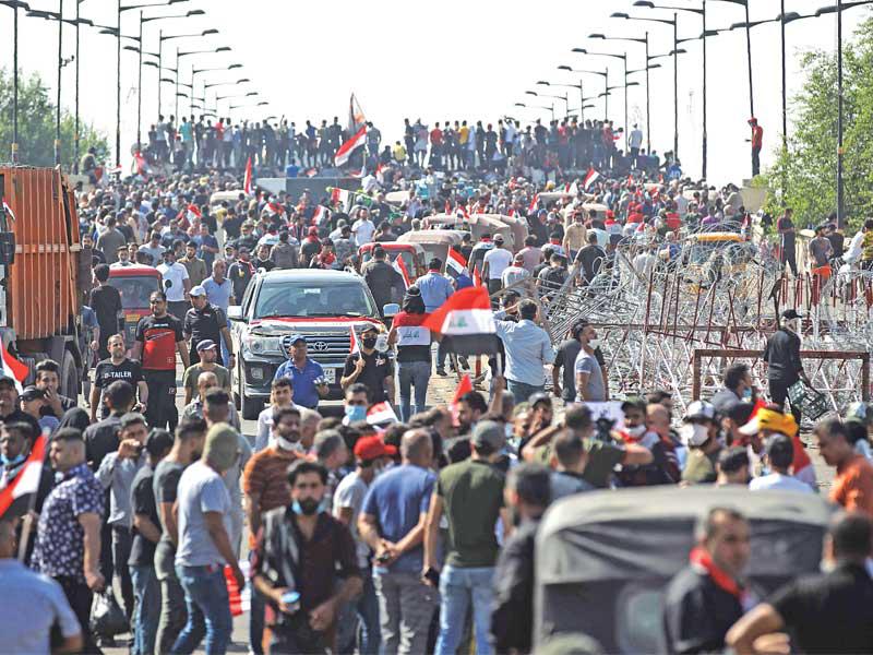عراقيون يتظاهرون عند جسر الجمهورية وسط بغداد أمس (أ ف ب)