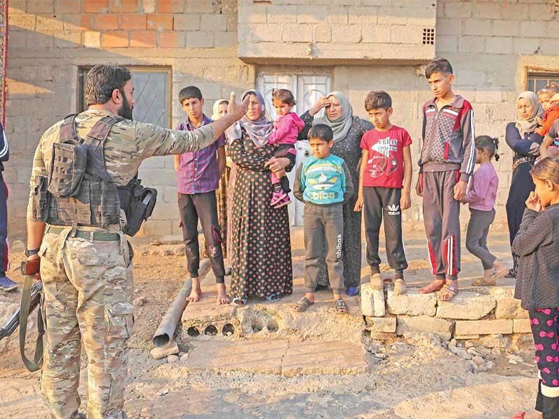 مقاتل موالي لتركيا يستجوب عائلة بقرية جان تمر شرق رأس العين أمس الأول (أ ف ب)