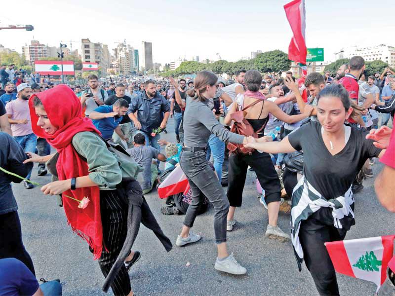 متظاهرون يفرّون من أمام أنصار حزب الله وأمل في وسط بيروت أمس           (أ ف ب)