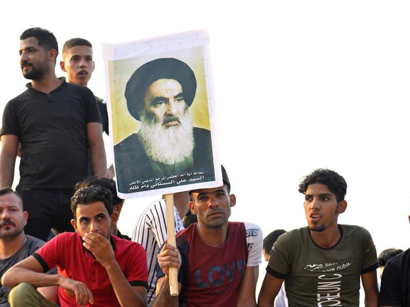 العراقيون يحملون صورة علي السيستاني خلال مظاهرة مناهضة للحكومة