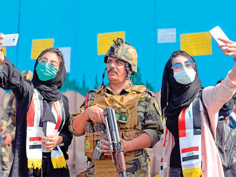 طالبتان عراقيتان تلتقطان «سيلفي» مع جندي خلال تظاهرة مناهضة للحكومة في منطقة الديوانية أمس   (أ ف ب)