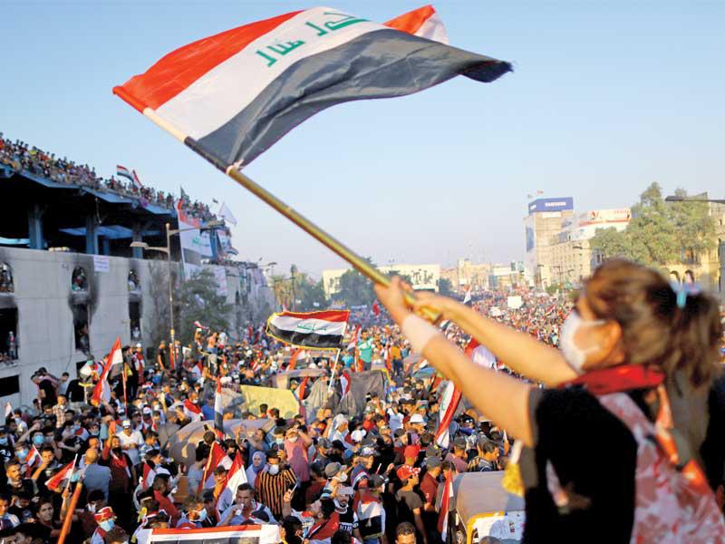 عراقية تلوح بعلم بلادها خلال تظاهرة في ساحة التحرير وسط بغداد أمس الأول (رويترز)