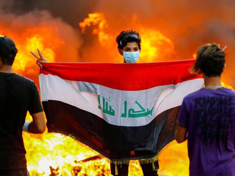 متظاهر يحمل العلم العراقي خلال الاحتجاجات المستمرة المناهضة للحكومة في بغداد ، العراق