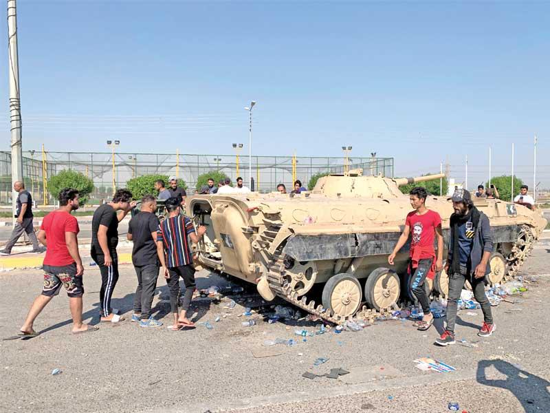 متظاهرون يسيطرون على آلية عسكرية بمحيط ميناء أم قصر في البصرة أمس (رويترز)