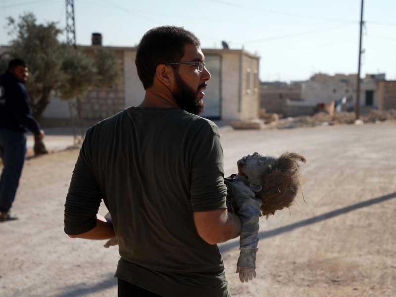 رجل يحمل جثة فتاة قُتلت في غارة جوية على قرية السحارة السورية في الريف غرب مدينة حلب