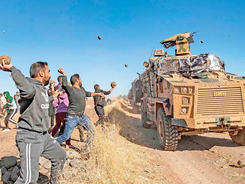 أكراد يرمون الحجارة على دورية تركية بالقرب من بلدة المعبدة بالحسكة أمس الأول (أ ف ب)