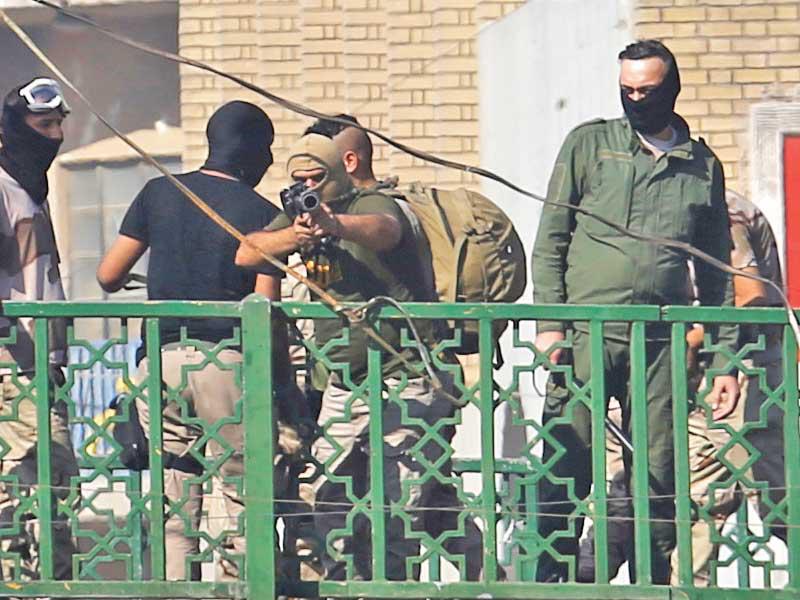 رجل أمن يصوِّب بندقيته باتجاه محتجين وسط بغداد أمسt (رويترز)