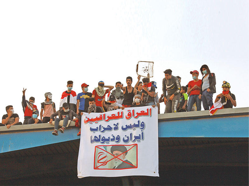 عراقيون إلى جانب لافتة مناهضة لخامنئي في ساحة التحرير ببغداد أمس (اي بي ايه)n