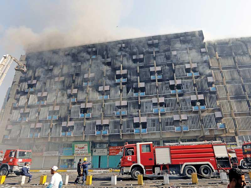 «الدفاع المدني» يكافح حريقاً شب في بناية قرب ساحات التظاهر بوسط بغداد أمس (رويترز)