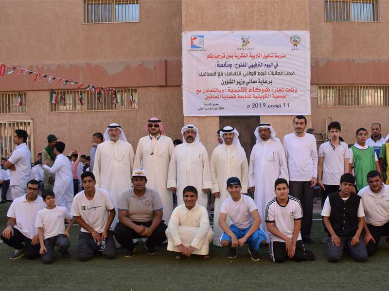 علي البغلي يتوسط مدير المدرسة خالد النقي وعلي ثويني أمين سر الجمعية الكويتية لمتابعة قضايا المعاقين مع مجموعة من الطلبة   