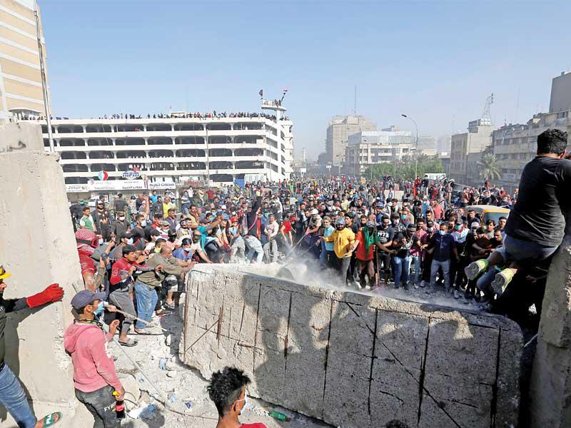محتجون يزيلون كتلاً خرسانية عند جسر السنك بعد تقهقر القوات الأمنية وسط بغداد أمس           (رويترز) 