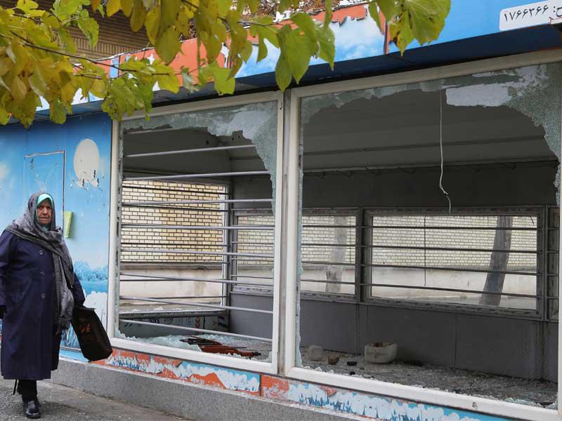 إيرانية تمر أمام واجهة محل حطمها المحتجون أمس بطهران (أ ف ب)