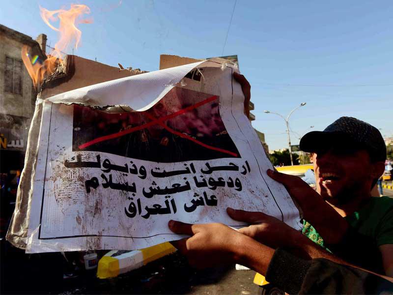 متظاهرون عراقيون يحرقون صور قائد «فيلق القدس» اللواء قاسم سليماني في بغداد (إي بي أيه)